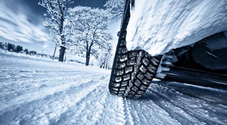 A closeup of snowy tires on a vehicle on a snow-covered road