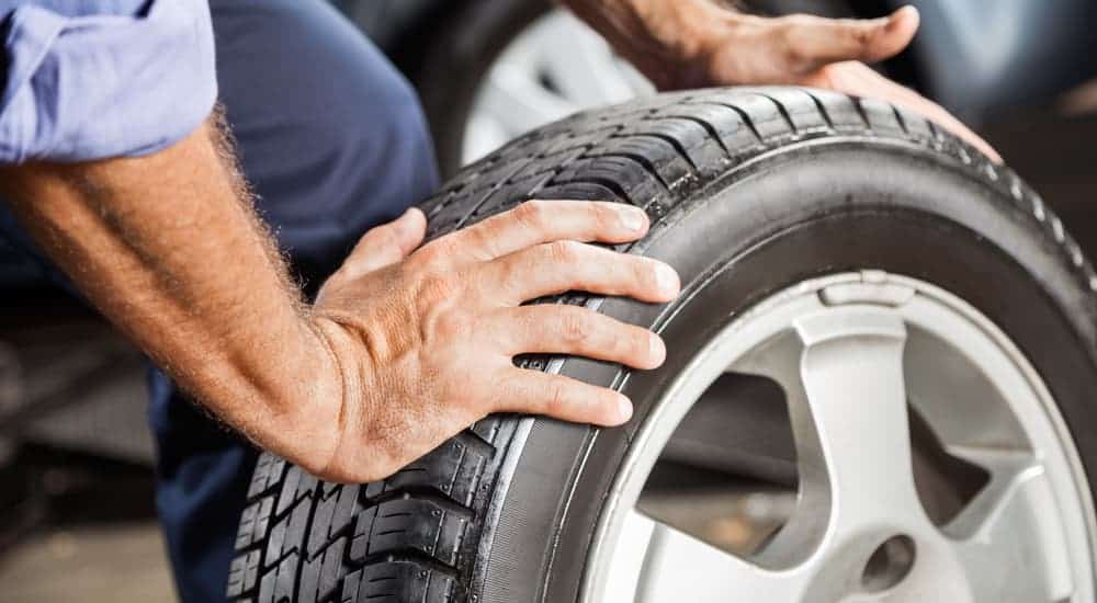 A mechanic is putting summer tires on a car. Summer tires are one of several types of tires.