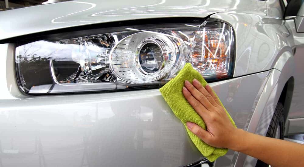A closeup of a hand wiping down a clean car is shown.
