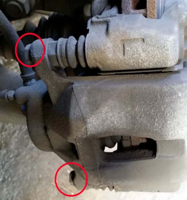 The location of the bolts to remove the caliper for a brake service are shown circled.