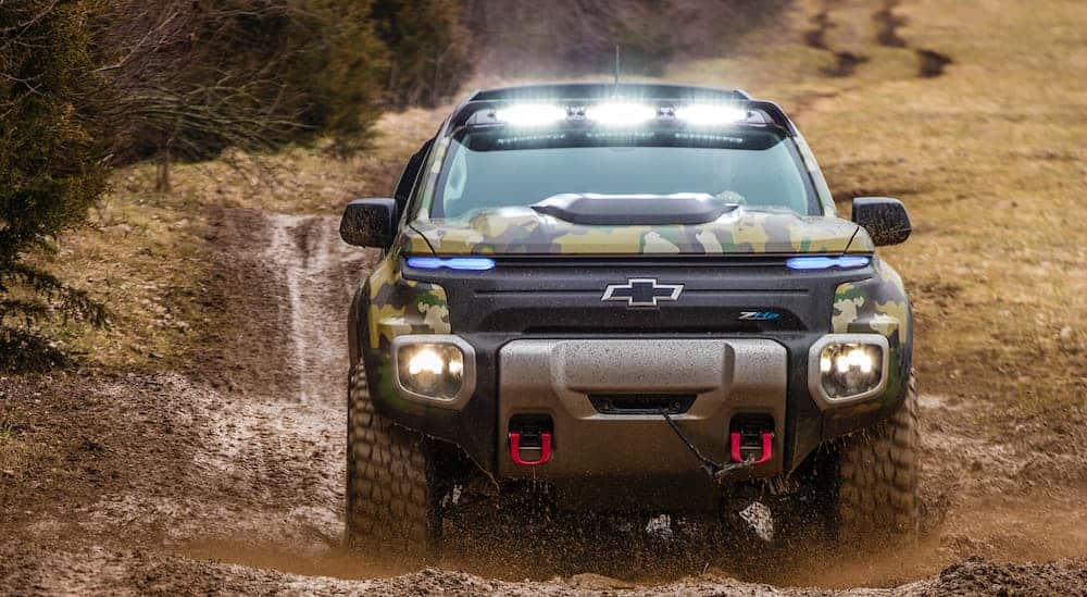 A modified Chevrolet Colorado ZH2 FuelCell is driving through mud with many truck accessories, including lights.