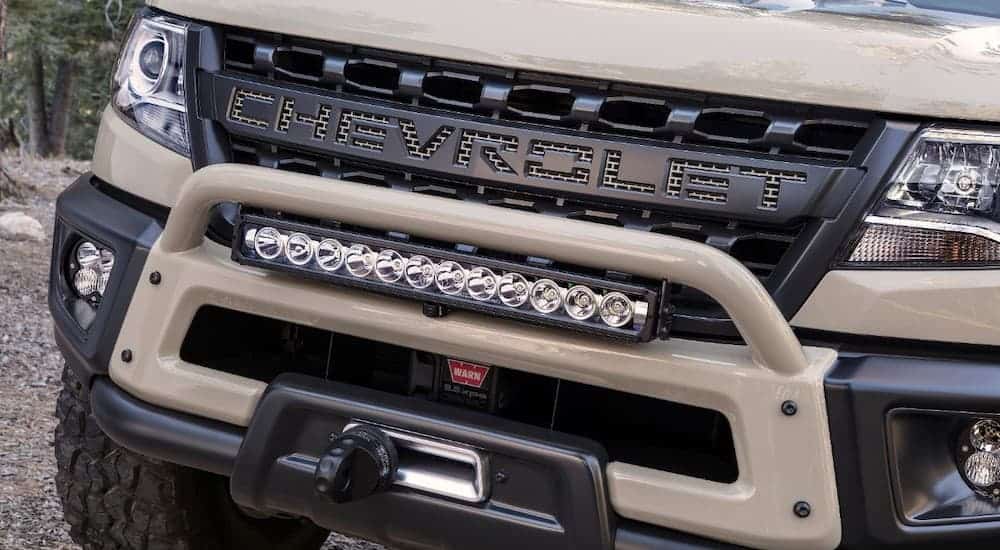 A close-up on the grille of a tan 2017 SEMA Chevy Colorado ZR2 is shown, featuring a fitted light bar.