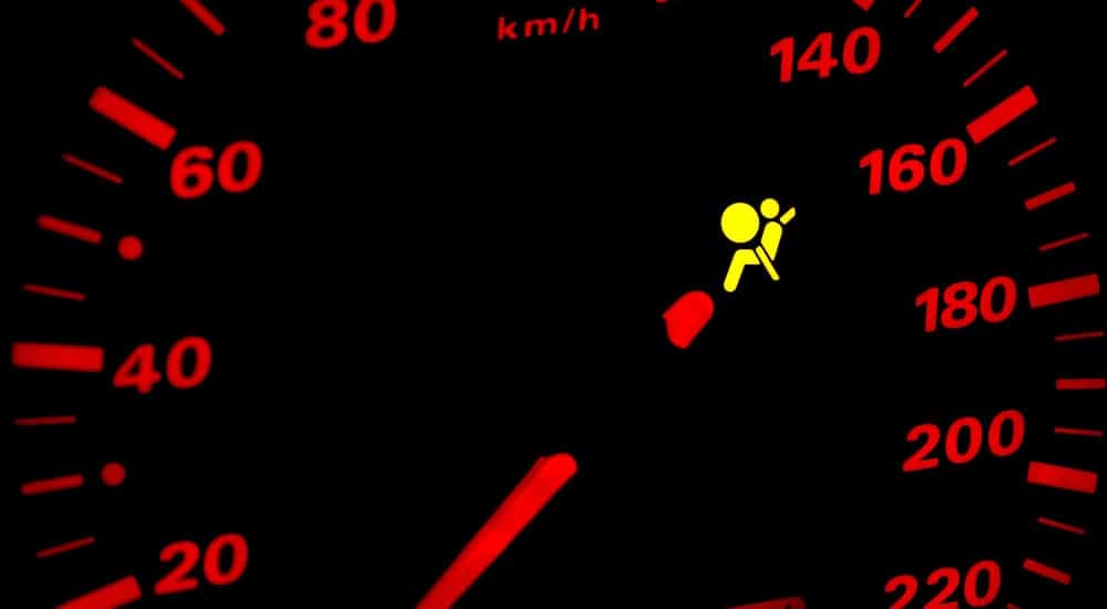 An airbag light is on on a black car dash.