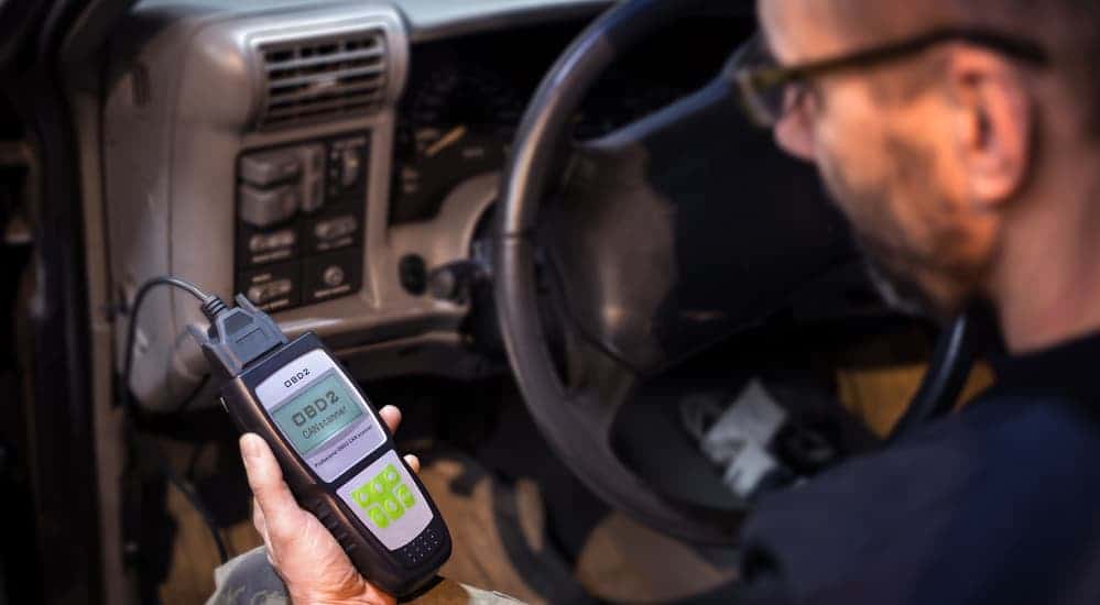 A mechanic is testing the OBD system with a code reader, the first thing you do when starting a car electrical repair. 