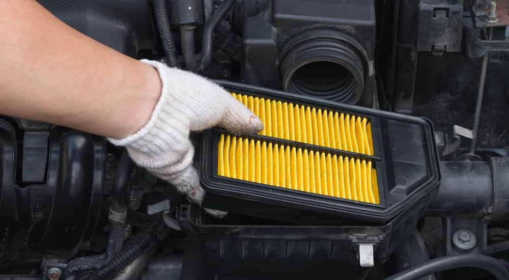 After searching how to change an air filter, a man is replacing his air filter.