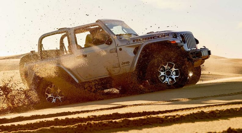 A silver 2020 Jeep Wrangler is driving through the desert.