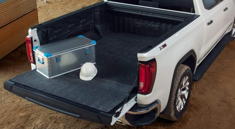 A birds eye view of a black bed mat inside the bed of a white GMC Sierra 1500.