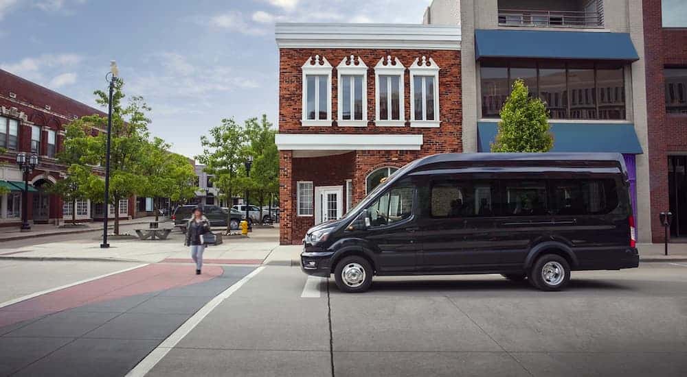 A black 2020 Ford Transit Hybrid is stopped at a crosswalk.