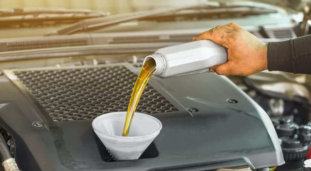 A close up is shown of a person pouring oil into a funnel.