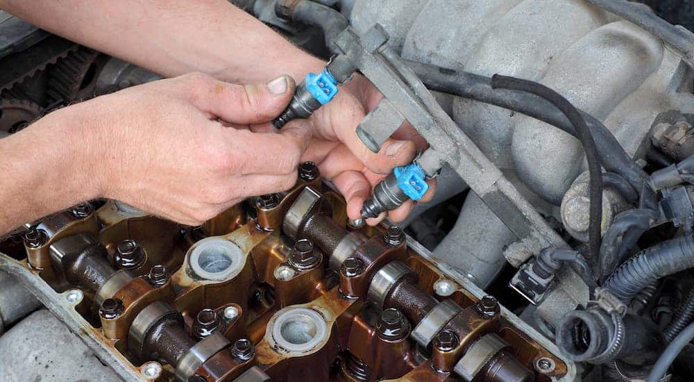 A mechanic is cleaning the fuel injectors in a car.