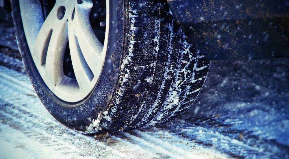 A closeup shows snow clinging to a car tire.
