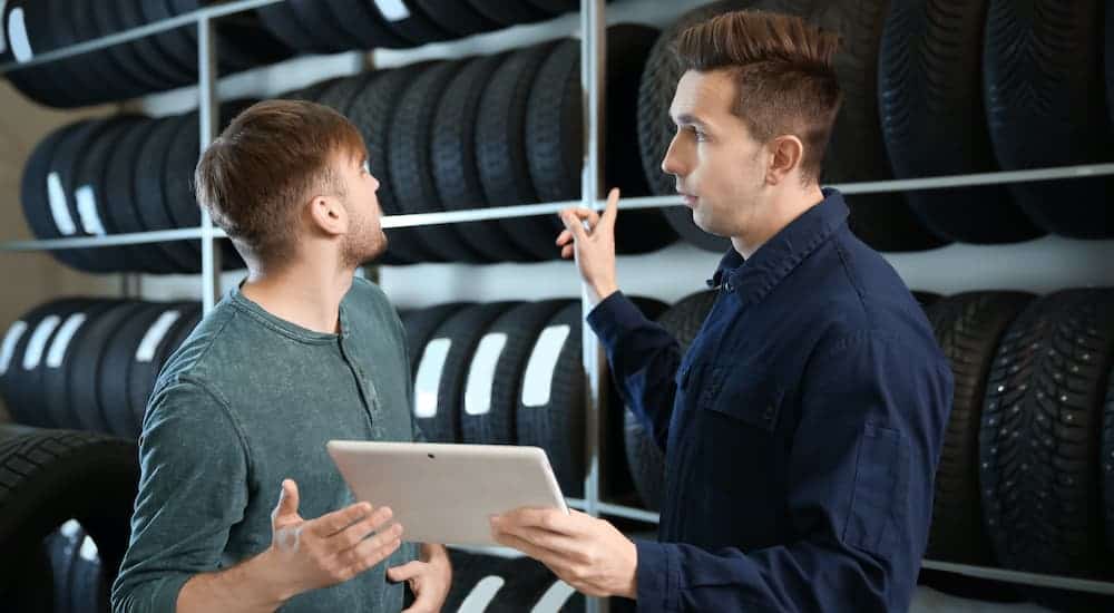 Two men are looking at a tablet discussing tire options at a tire shop near you.