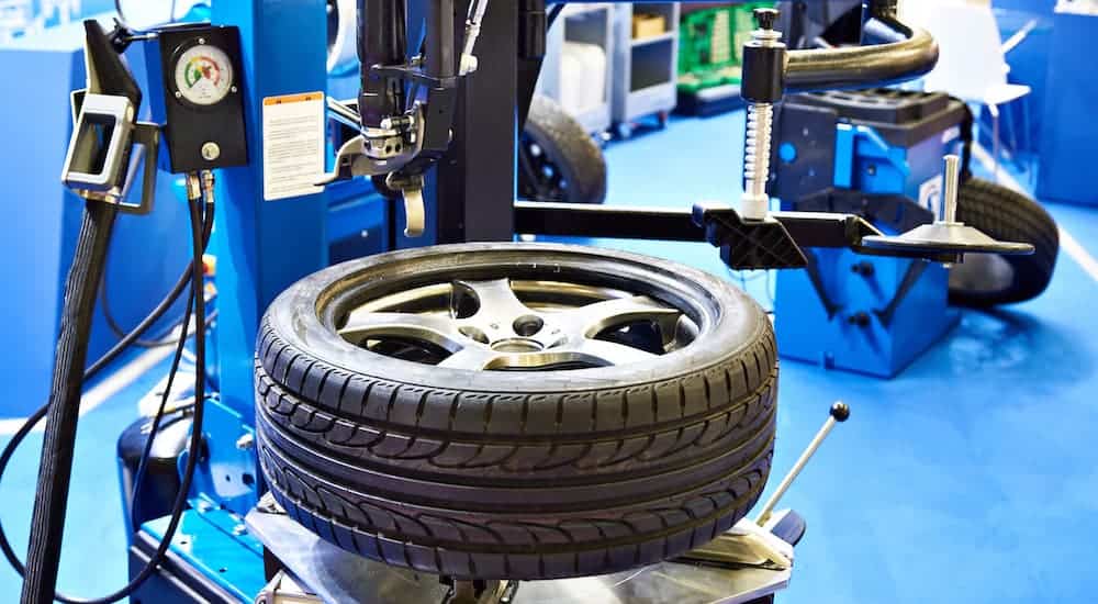 An alloy rim is being debeaded with a tire machine at a tire shop.