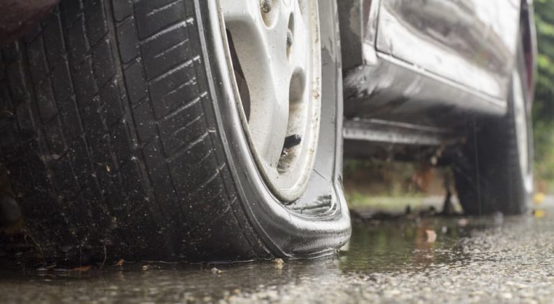 Close up image of a flat tire in a wet road