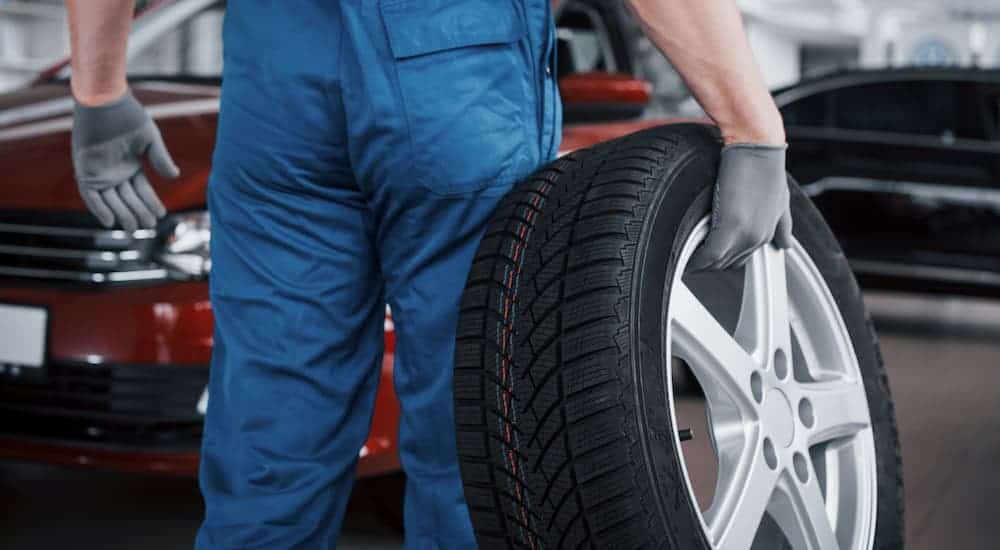 A mechanic holding a tire mounted on an alloy rim