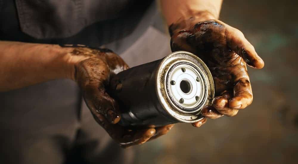 A mechanic is holding a used spin on oil filter.