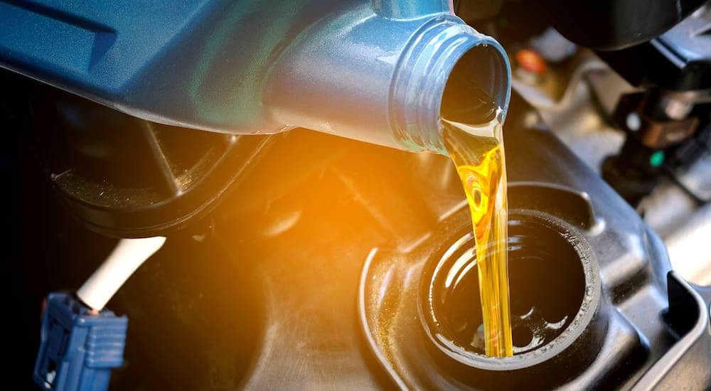 A closeup shows oil being poured into an engine during a Nissan service.