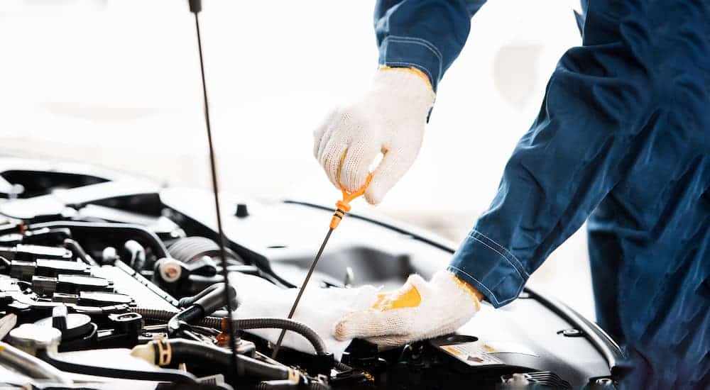A gloved hand is checking the oil in a car at a Toyota service department.