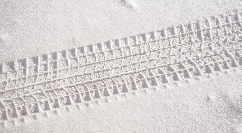 A closeup shows tire tracks in snow.