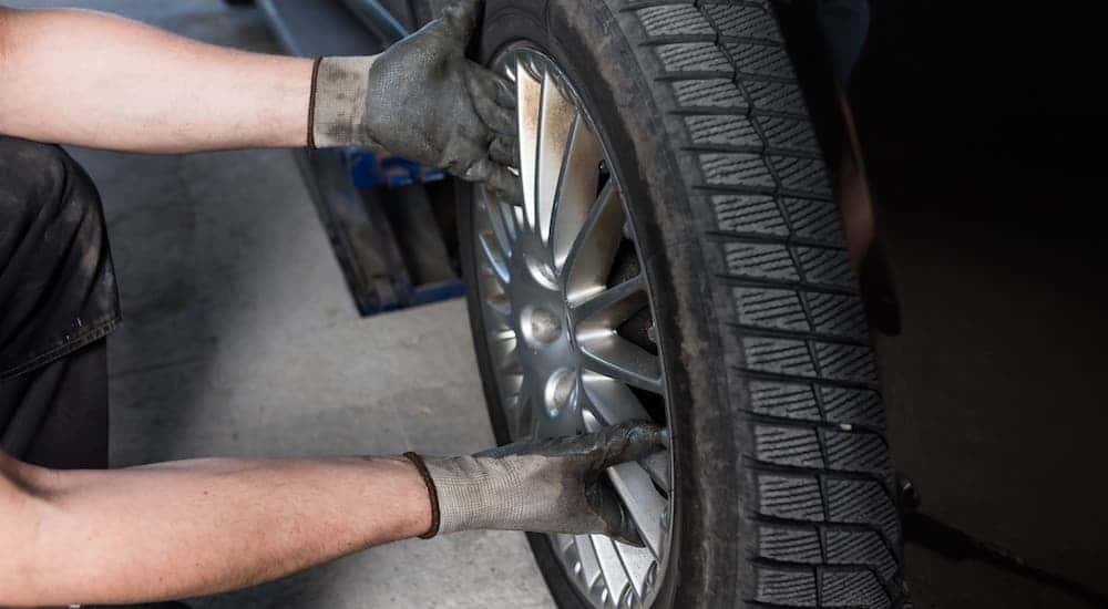 A closeup shows a mechanic putting cheap tires on a car.