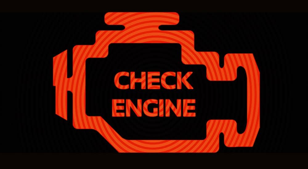 A close up shows an orange illuminated check engine light.