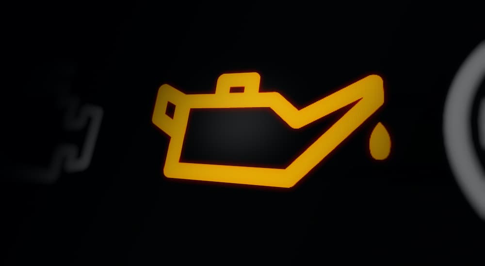 A close up shows an illuminated yellow low oil icon.