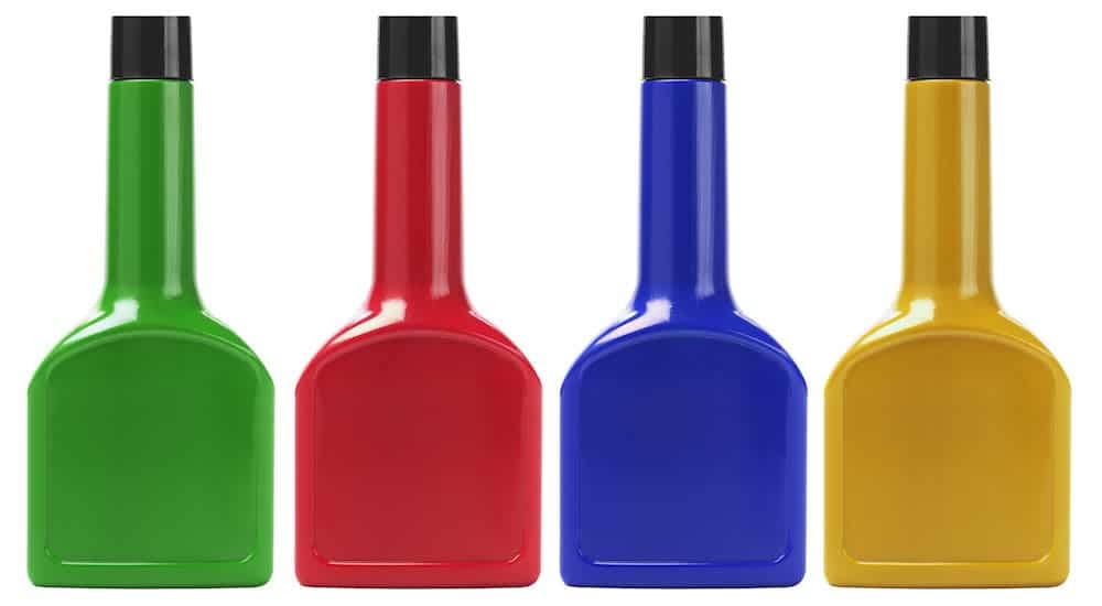 A green, a red, a blue, and a yellow fuel additive bottle are on a white background.