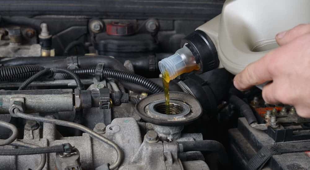 A close up shows oil being poured in to an engine.