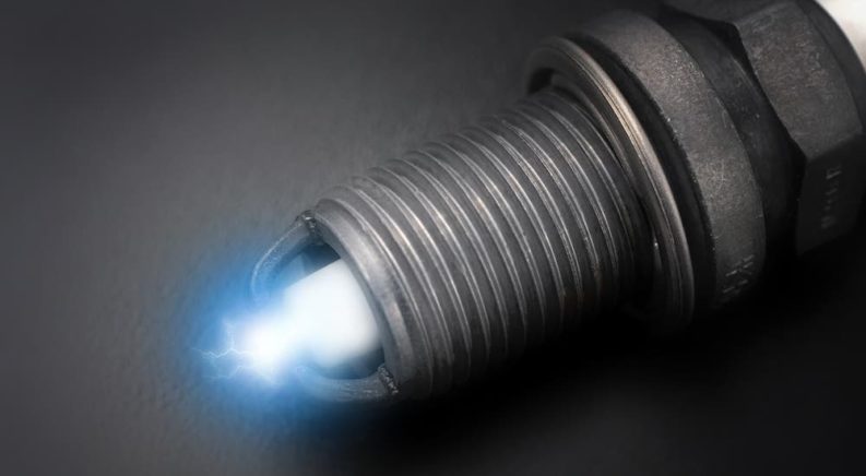 A closeup shows the spark on a spark plug.