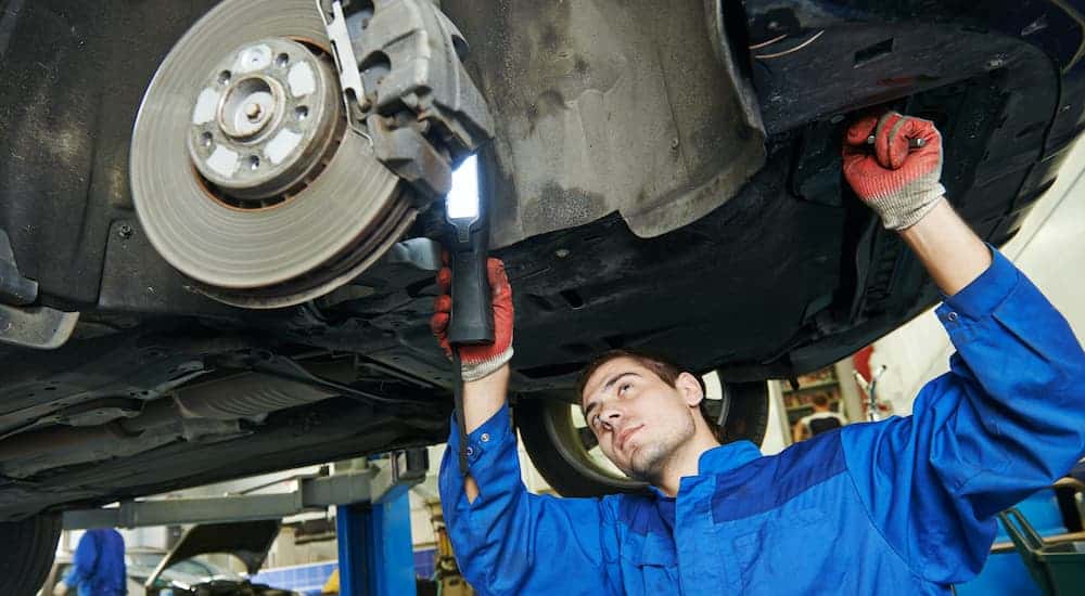 A mechanic in a blue jumpsuit is inspecting brakes during a Toyota service near you.