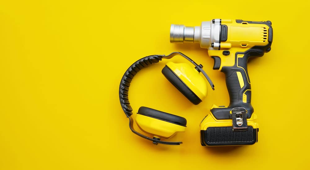 A yellow Impact Wrench is shown with a pair of safety earmuffs.
