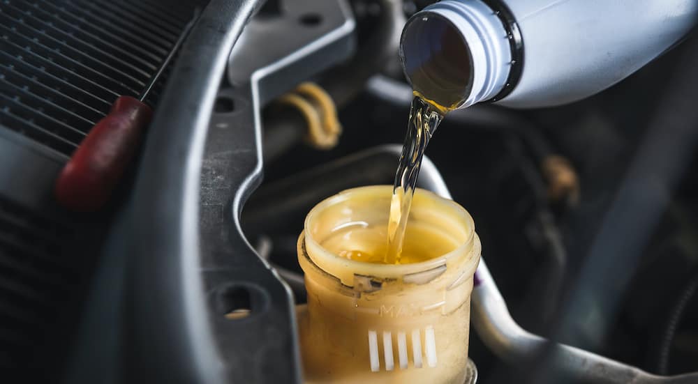 Brake fluid is being poured into a reservoir during a Nissan brake service.