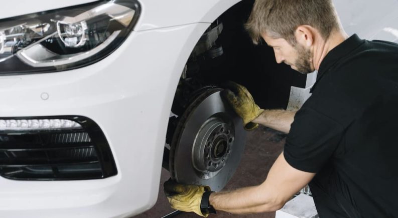 A gloved mechanic is replacing a brake rotor during a Toyota brake service.