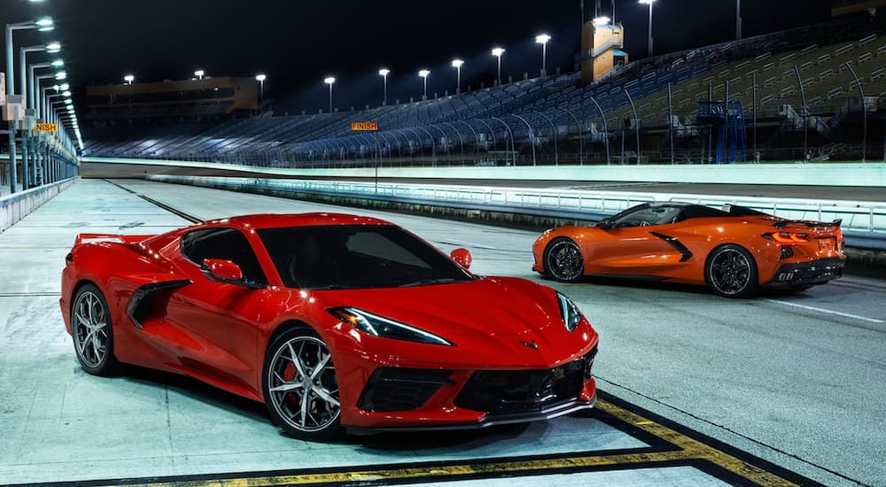 A red and an orange 2021 Corvette are parked on a racetrack.