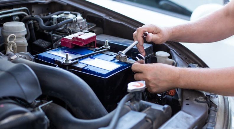 A person is tightening a bolt on a car battery.