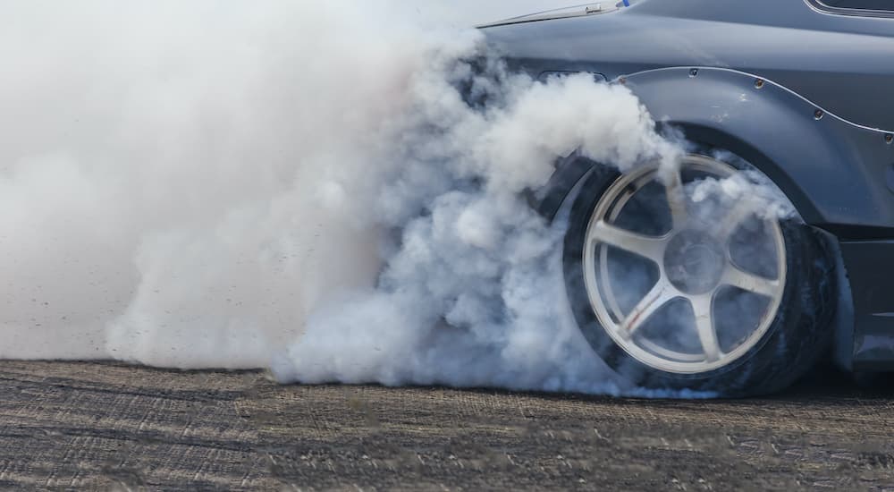 A close up shows a rear wheel doing a burn out.
