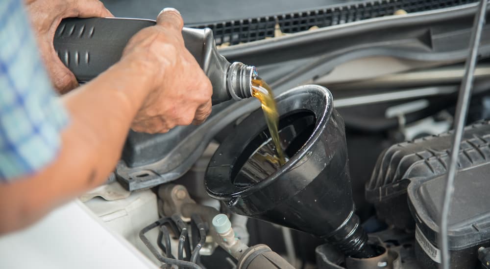 A man is funneling oil into his truck during an oil change.