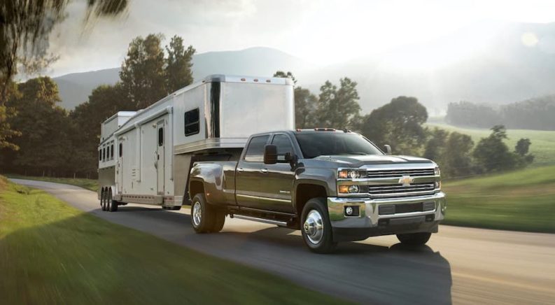 A black 2016 Chevy Silverado 3500 HD is shown towing a camper after buying cheap tires for towing.