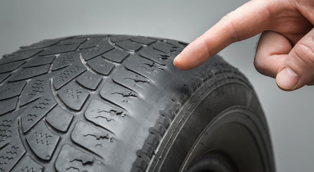 A tire with a worn out tread is shown in close up.