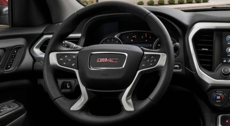 The black interior of a 2022 GMC Acadia shows the steering wheel in close up.
