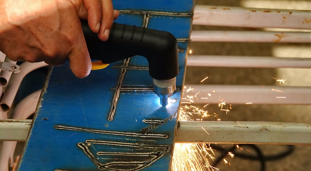 A plasma cutter is shown being used on a metal sheet.