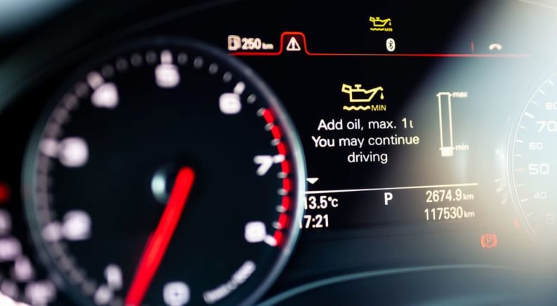 A car dashboard warning light that says "add oil" is shown.