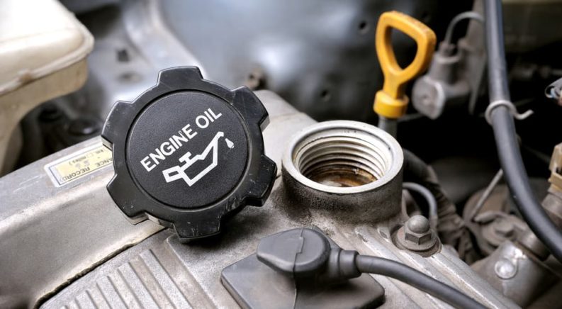 An engine oil cap is shown removed and placed and next to the dip stick.