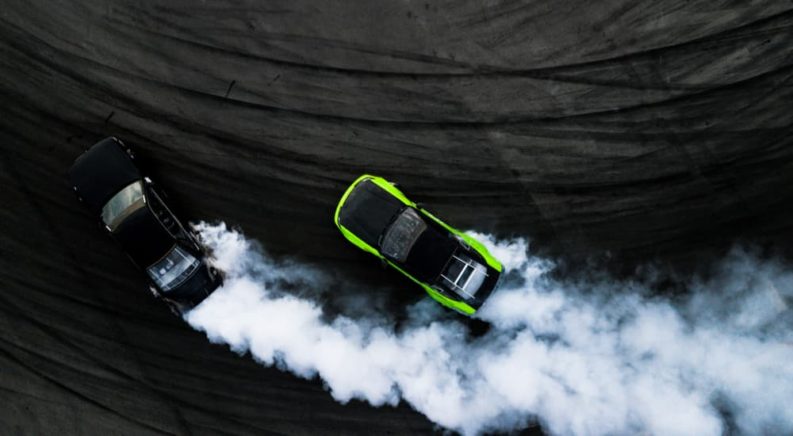 A black and green car are shown from a high view on a racetrack.