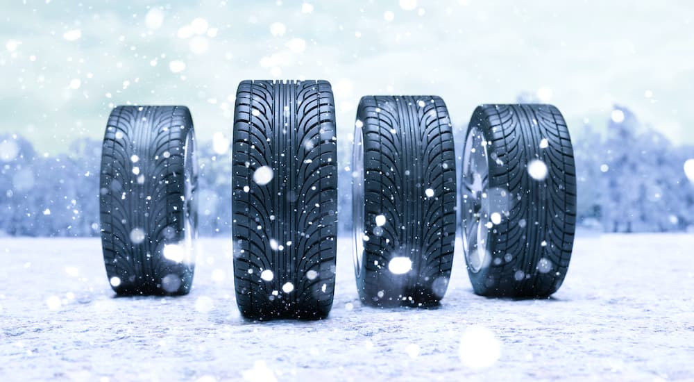 Four snow tires are shown standing in snow.