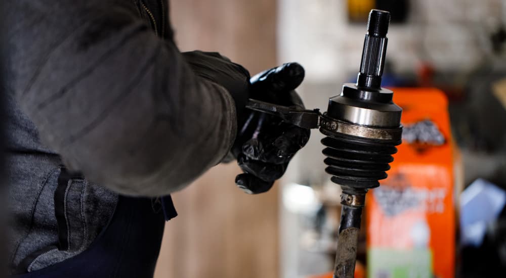 A mechanic is shown holding a vehicle's CV joint.