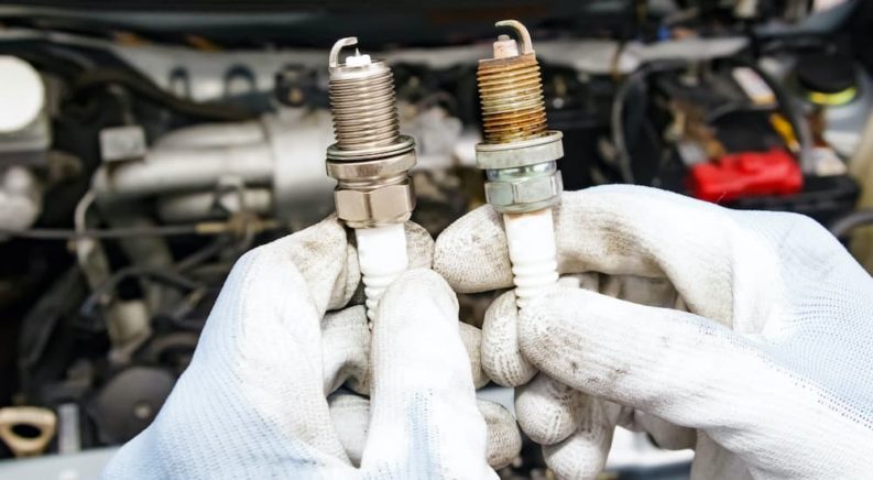 A new and old spark plug are compared in a side by side during a Nissan service.