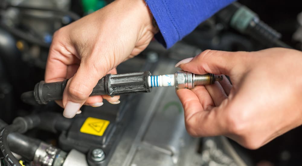 A mechanic is shown changing a spark plug during a Nissan service.