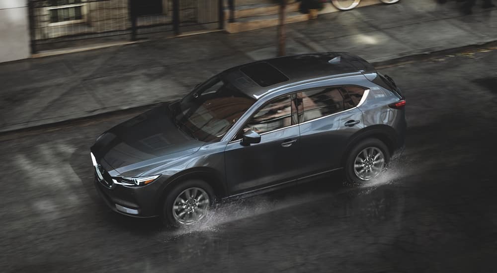 A grey 2021 Mazda CX-5 is shown driving on a city street.