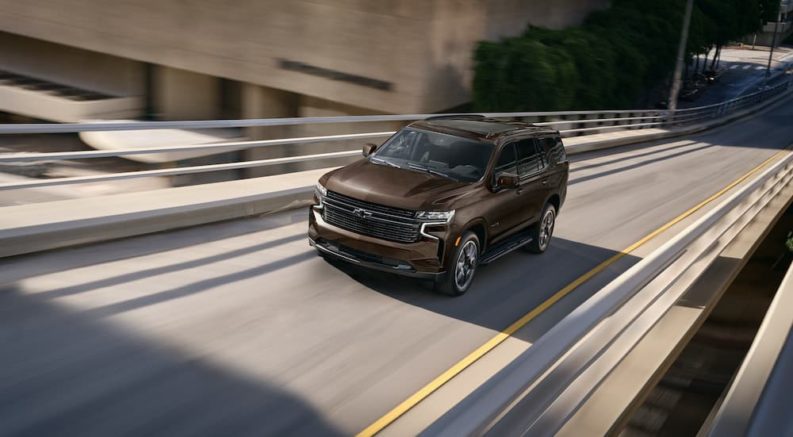 A brown 2022 Chevy Tahoe is shown from a high angle driving on a ramp.